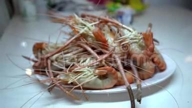 一家海鲜店里的人把煮好的虾放在盘子里。 拍摄特写。